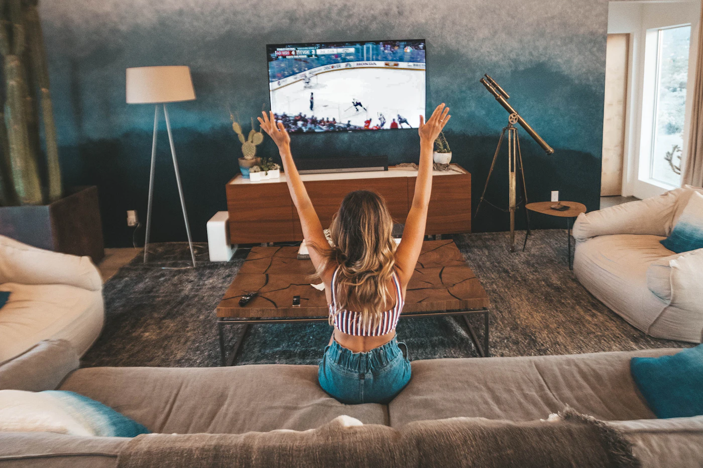 Viewer cheering in front of a big TV in a living room