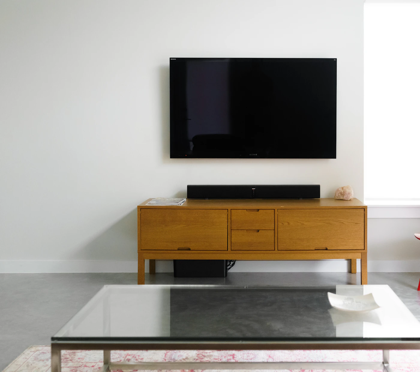 Minimal living room with a wall-mounted TV above a wooden console